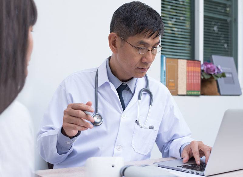 patient visits doctor working on laptop